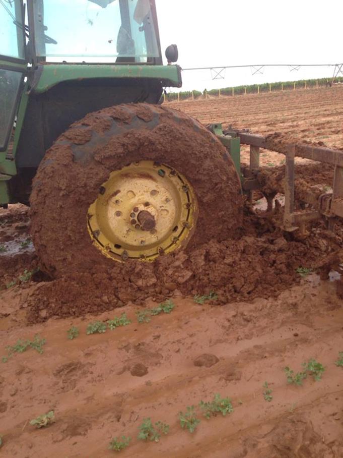 Large tractor with wheels stuck in the mud.